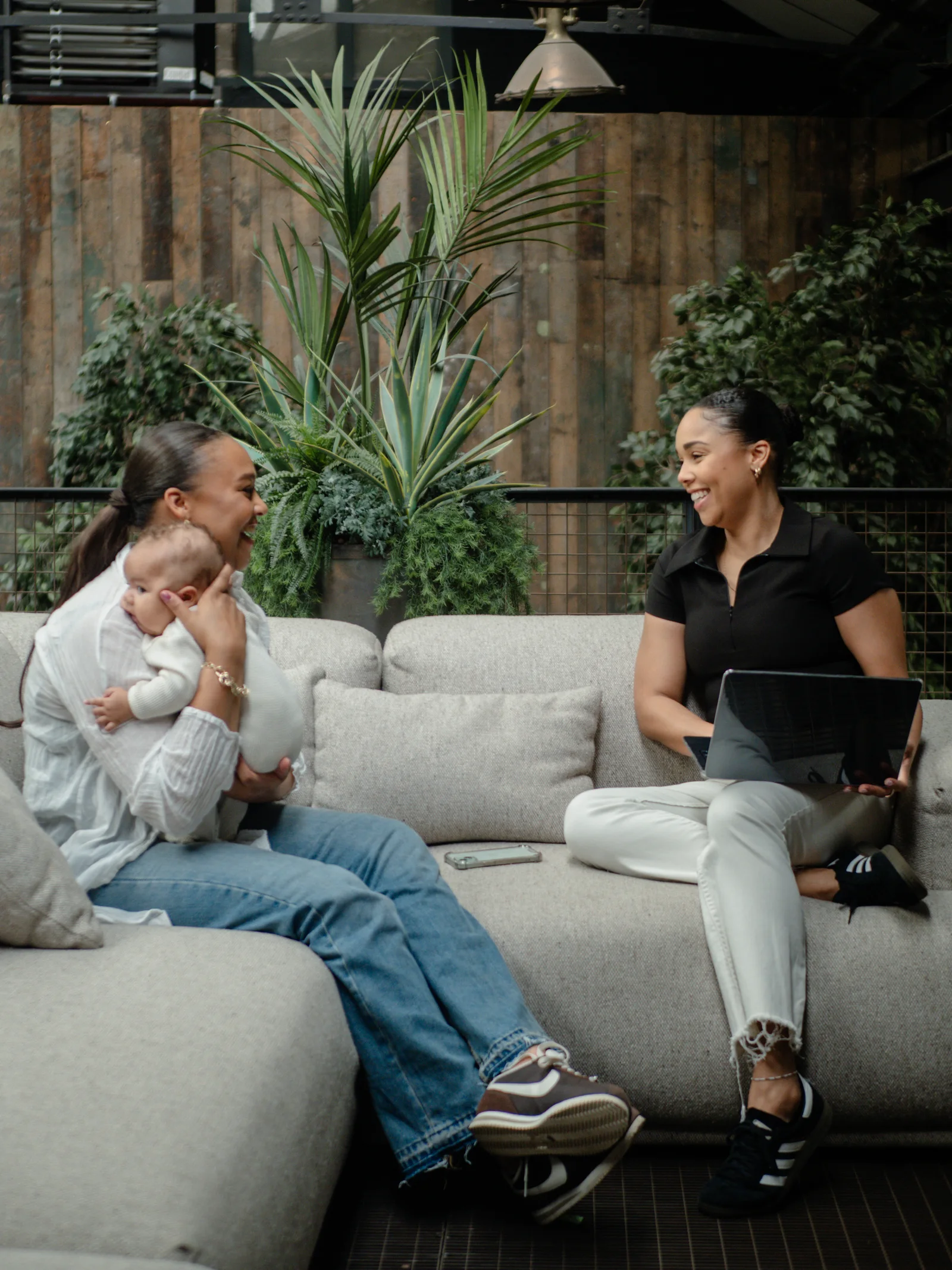 Cubbi founders Olivia and Tanyka Davson working together on a sofa with a baby