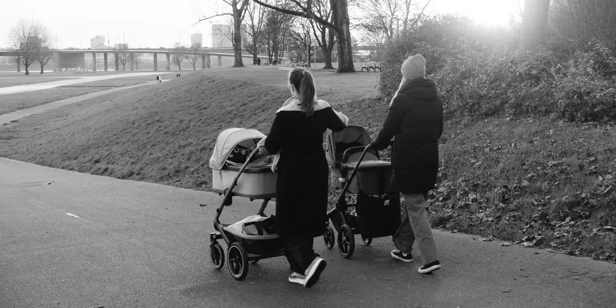 Two mums walking in the park with prams