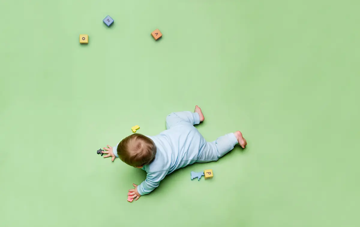 Baby on green background playing with toys