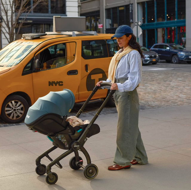 Mum pushing Doona pram in the city