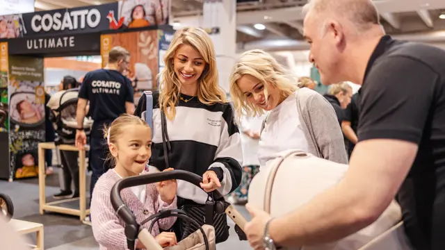 Parents chatting at a baby show stand with their toddler