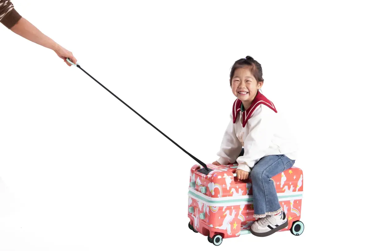 A child riding a pull-along kids' suitcase