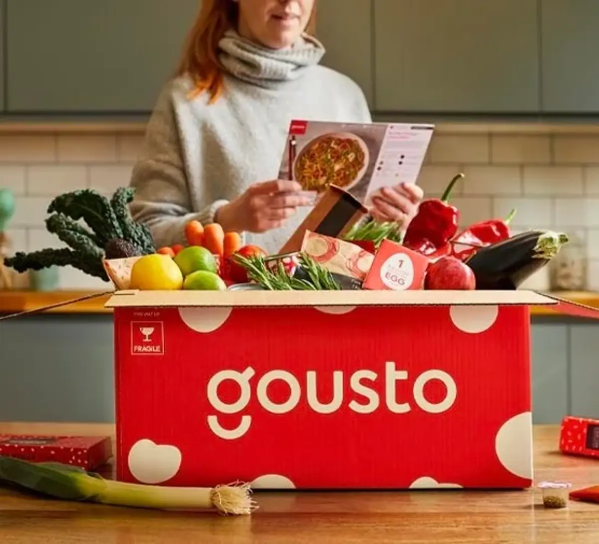 A red Gousto recipe box packed with fresh ingredients