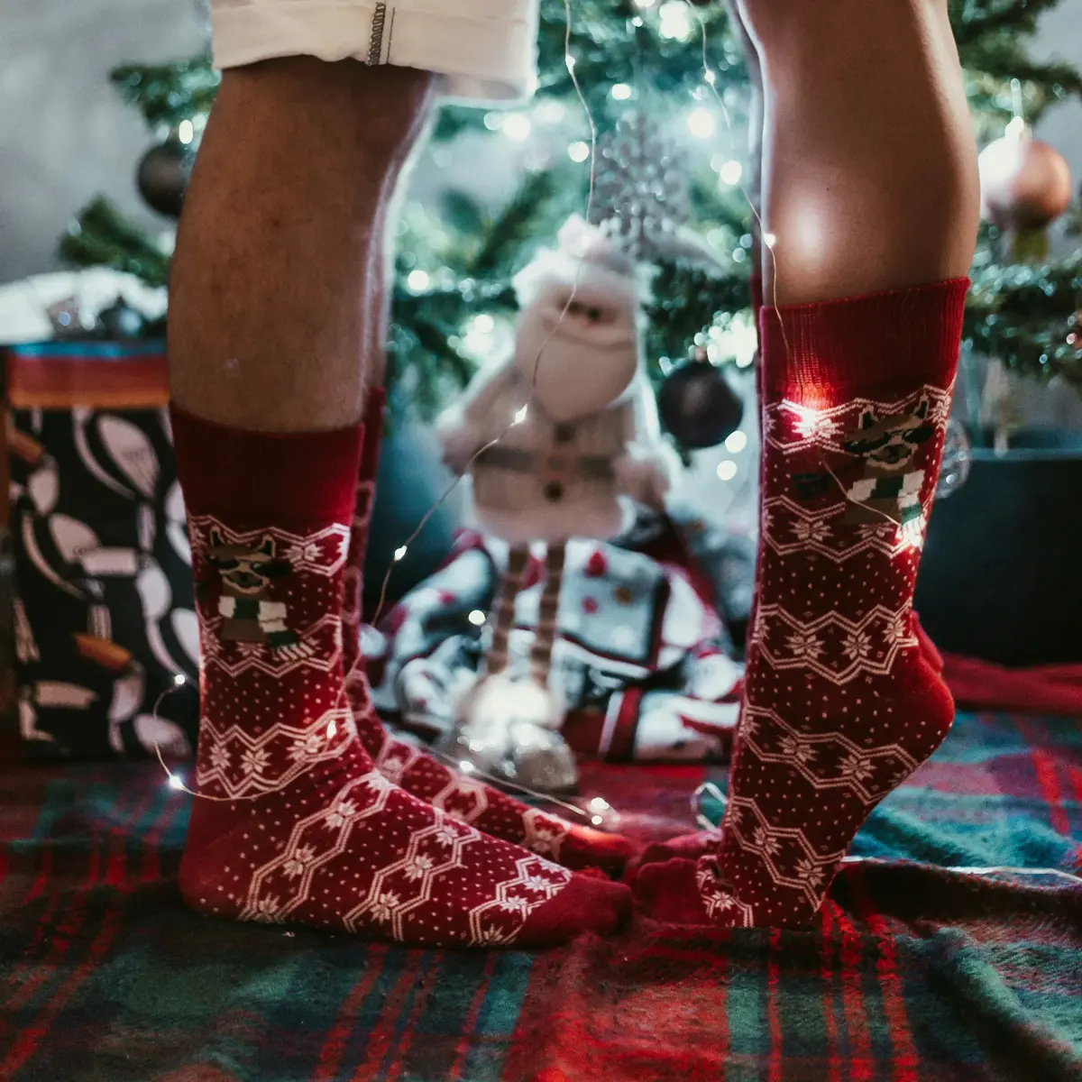 A couple's feet in matching Christmas socks by the tree