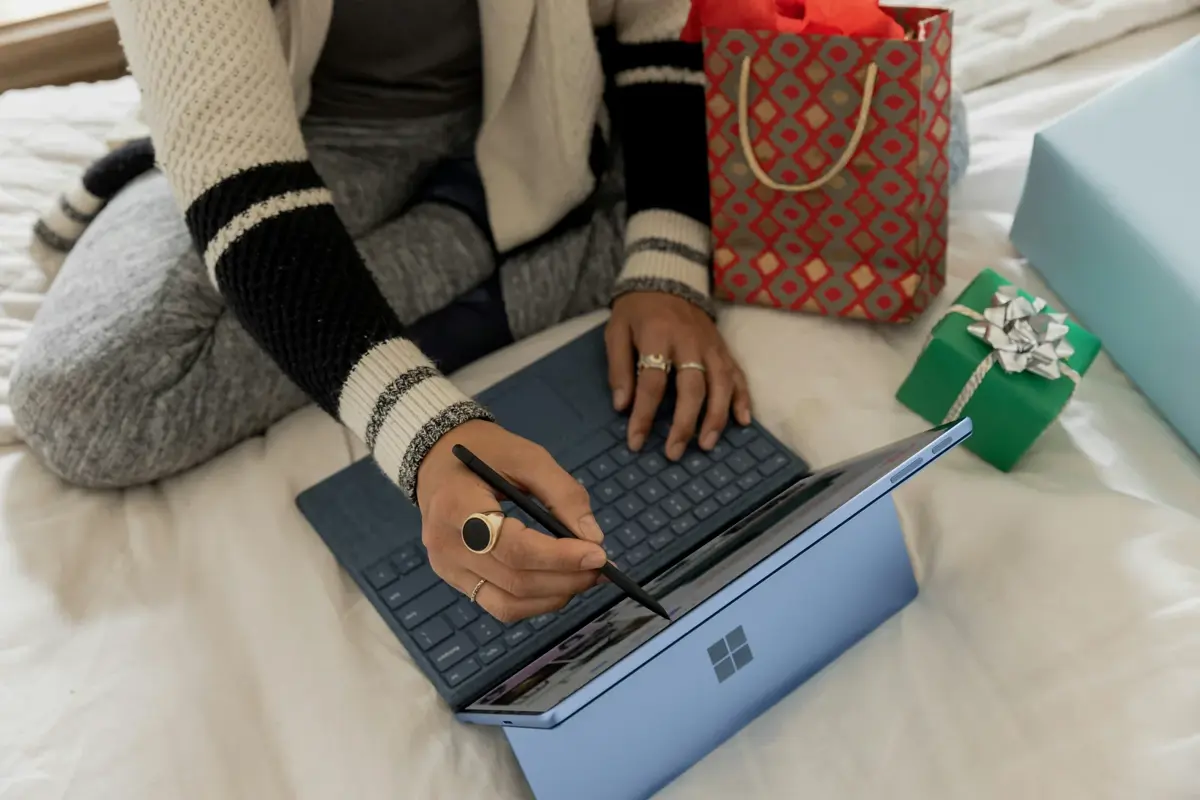 Writing Christmas cards beside a laptop and gifts