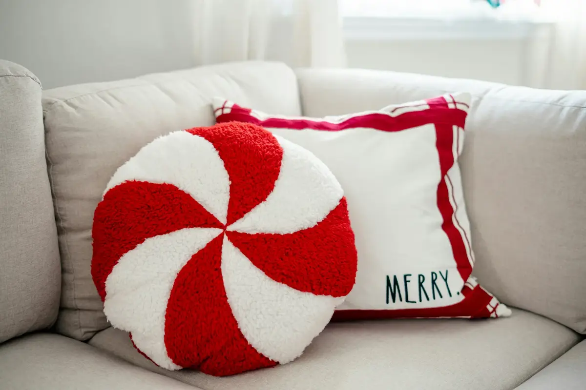 Peppermint-swirl and MERRY cushions on a sofa