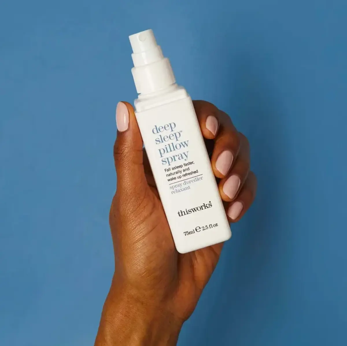 A hand holding This Works deep sleep pillow spray