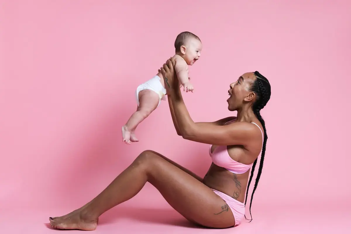 A mum in pink lifting her baby overhead