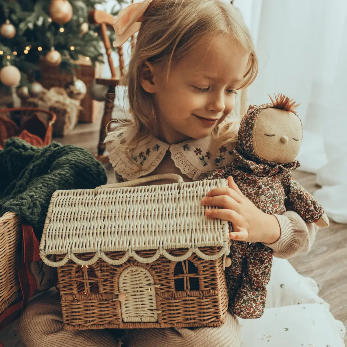 A child opening a gingerbread-house hamper by the tree