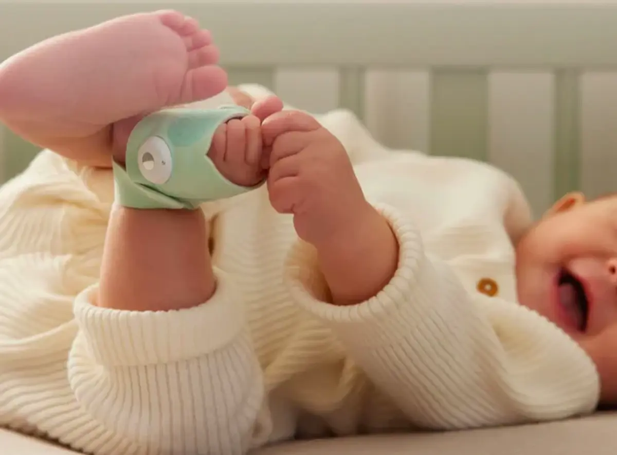 A baby's feet wearing soft ankle rattles in a cot
